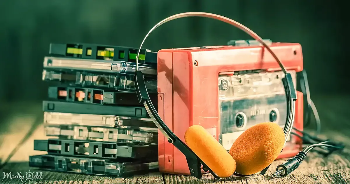 A red boombox with headphones and a stack of cassette tapes on a textured surface.