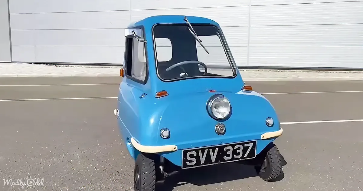 A bright blue, vintage, compact car with a single headlight and license plate SVV 337 is parked in a lot.