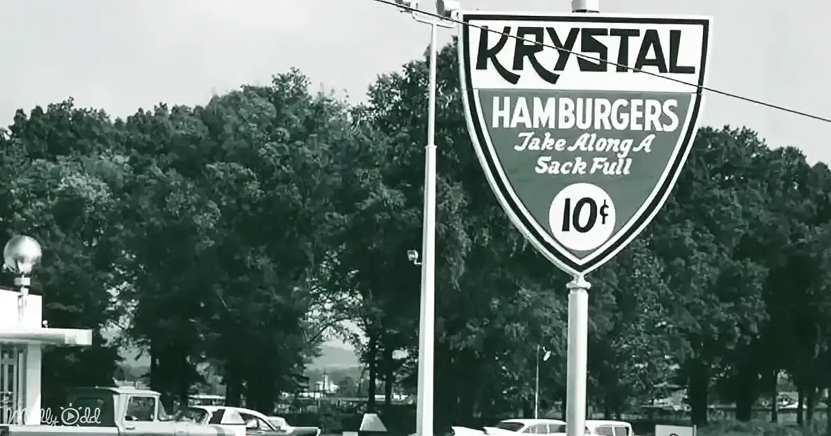 A vintage Krystal sign advertises hamburgers for 10 cents, with trees and cars in the background.