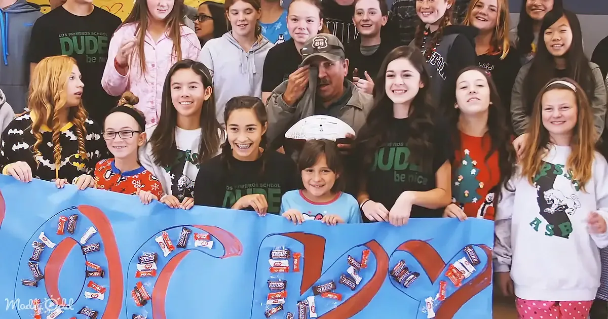 A group of children and an adult hold a banner with the word "OCTOBER" spelled out using candy bars.