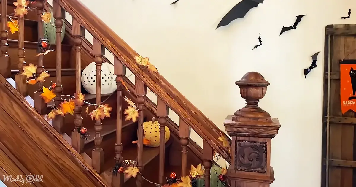Decorated staircase with autumn leaves, pumpkins, and bats on the wall, creating a festive Halloween atmosphere.
