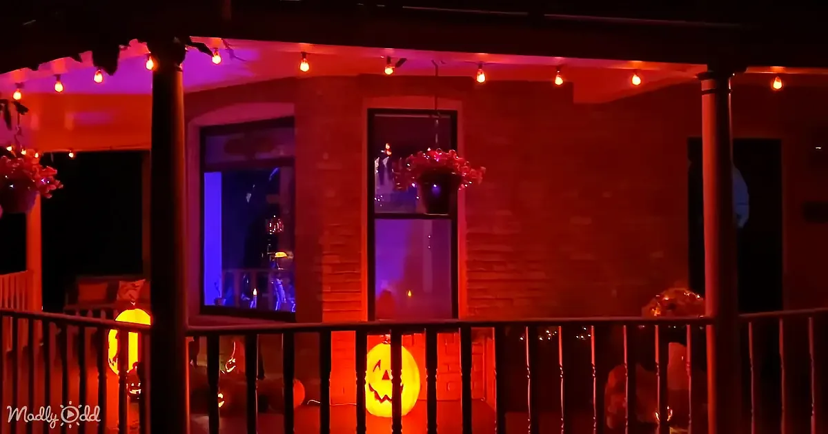 A porch decorated with Halloween lights and pumpkins, creating a spooky ambiance.