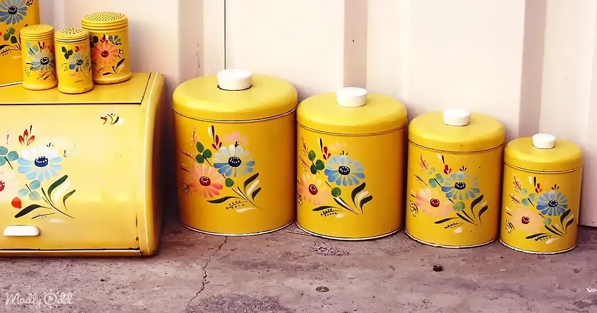 Bright yellow vintage kitchen canisters with floral designs sit neatly on a concrete surface.