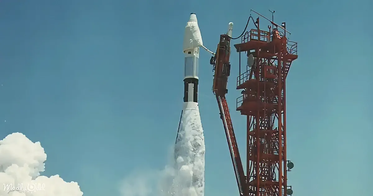 A rocket launches into the sky, leaving a trail of smoke, with a red support structure nearby.