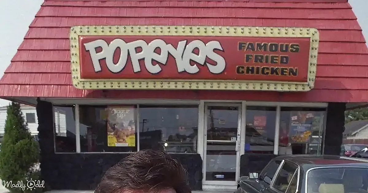 A Popeyes Fried Chicken restaurant with a red sign and retro-style marquee lights.