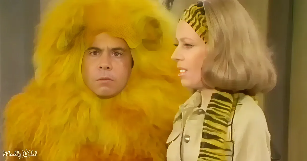 A person in a yellow lion costume stands next to another person with blonde hair and a striped shirt.
