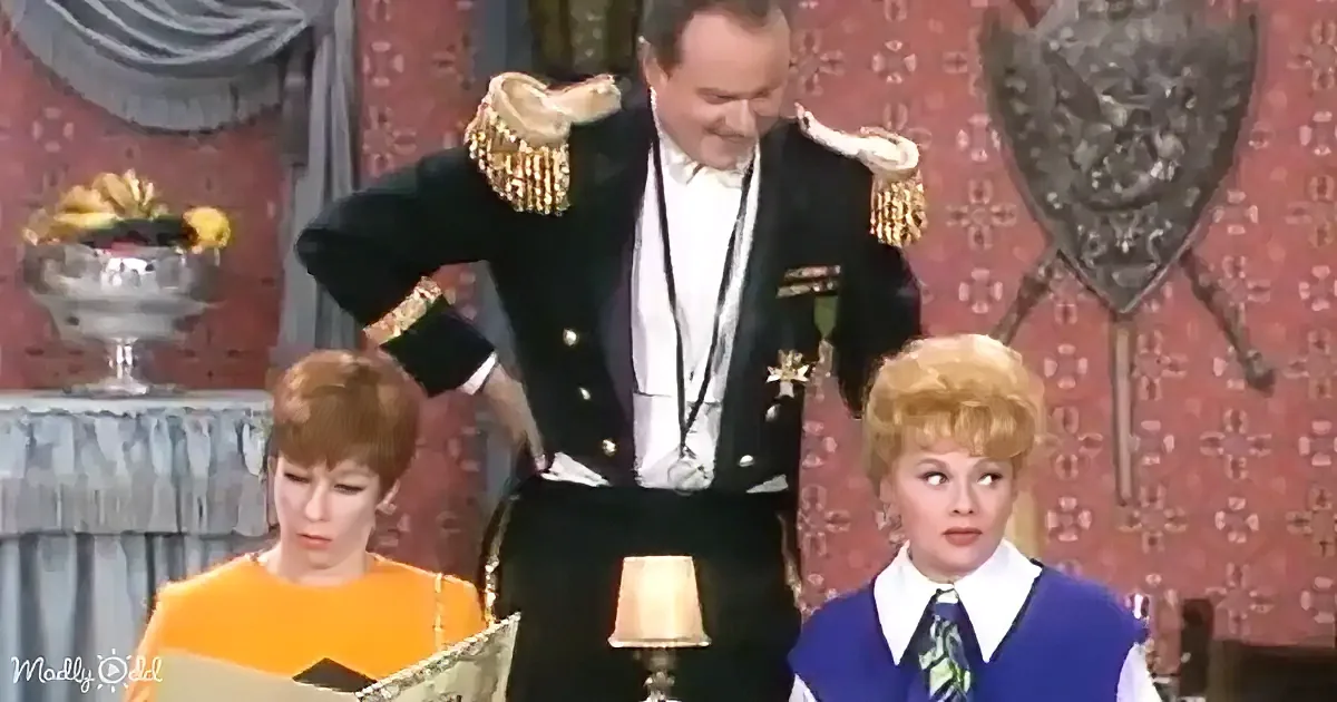 A man in a formal military-style uniform stands with hands on hips, flanked by two women in vintage attire.
