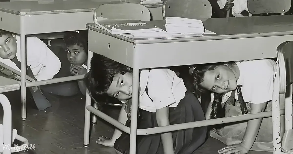 Children hiding under desks in a classroom, likely practicing for an emergency drill.