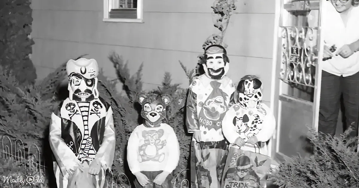 A group of people in elaborate costumes, including a pirate and a clown, stand together in front of a building.