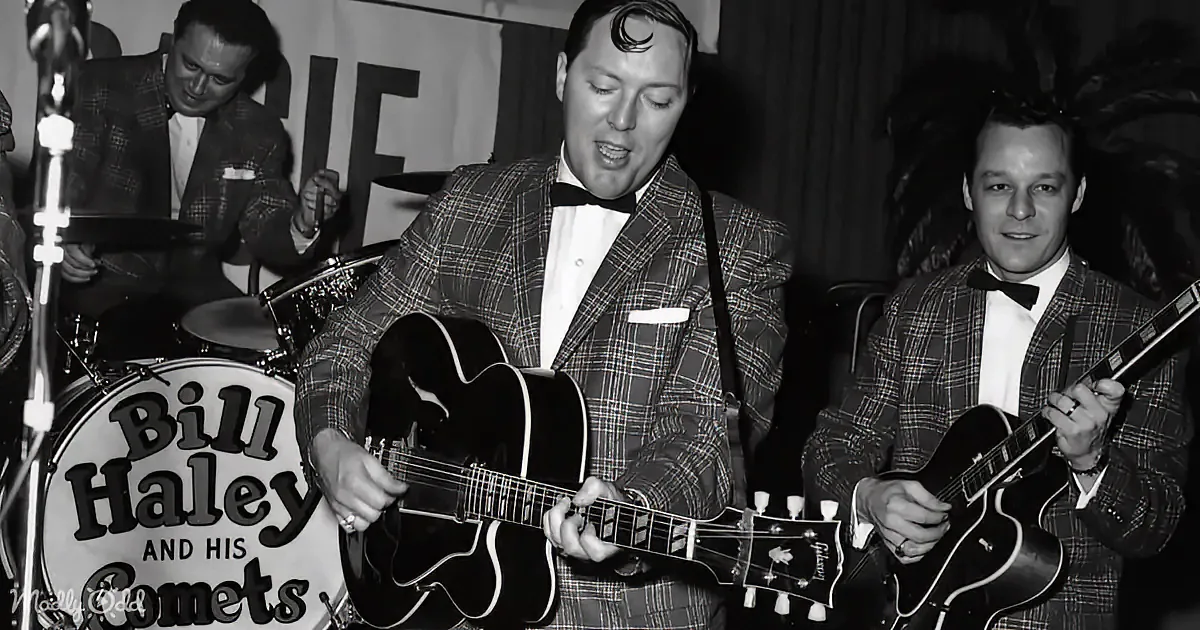 Bill Haley in a plaid suit plays guitar with his band, "Bill Haley and His Comets," in a vintage performance.