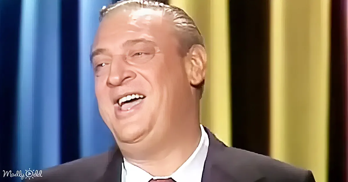 A man in a suit and tie is smiling widely, with a blue and yellow background.