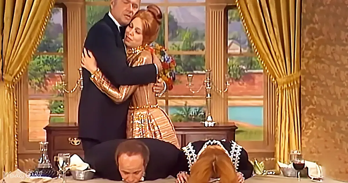 A man and woman embrace warmly while two others bow on the floor in a formal setting.