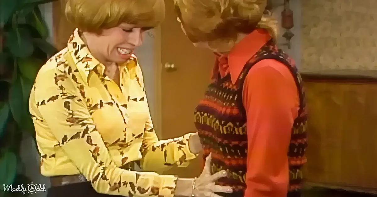 Two women in retro attire are interacting, one in a yellow patterned shirt, the other in a red and black sweater vest.