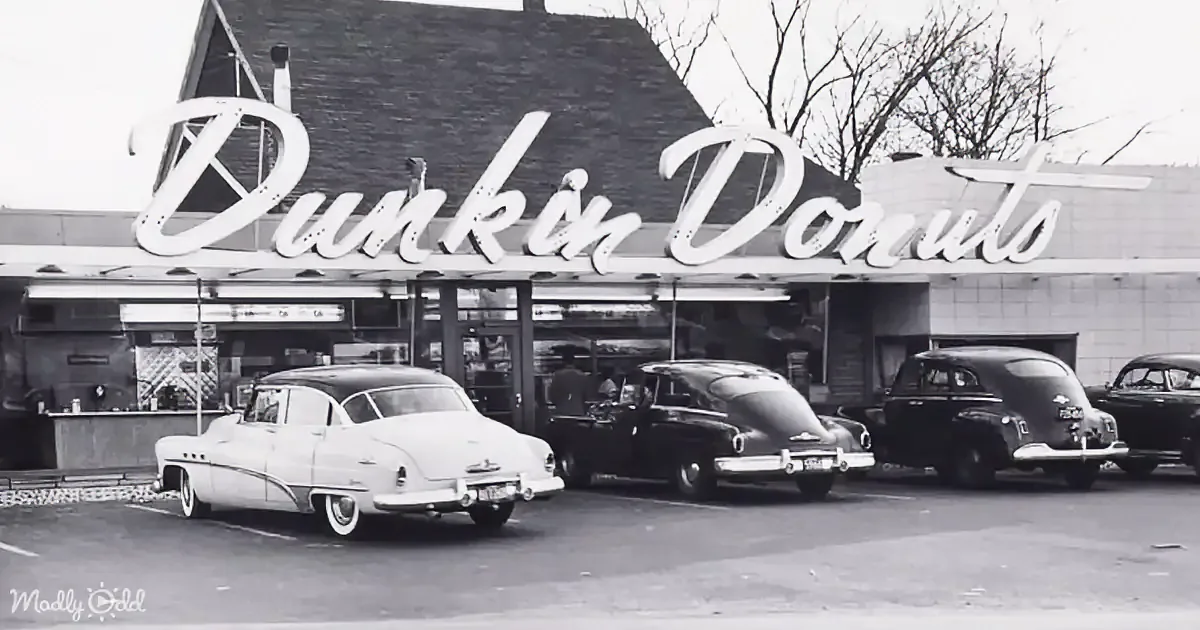 Vintage Dunkin' Donuts sign with classic cars parked in front.