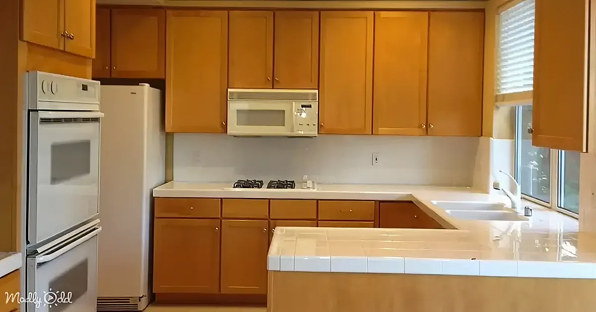 A kitchen with light wood cabinets, white appliances, and a tiled island.