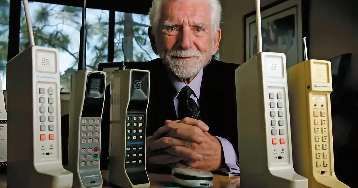 A man in a suit holds a large, old-fashioned phone to his ear on a busy city street.