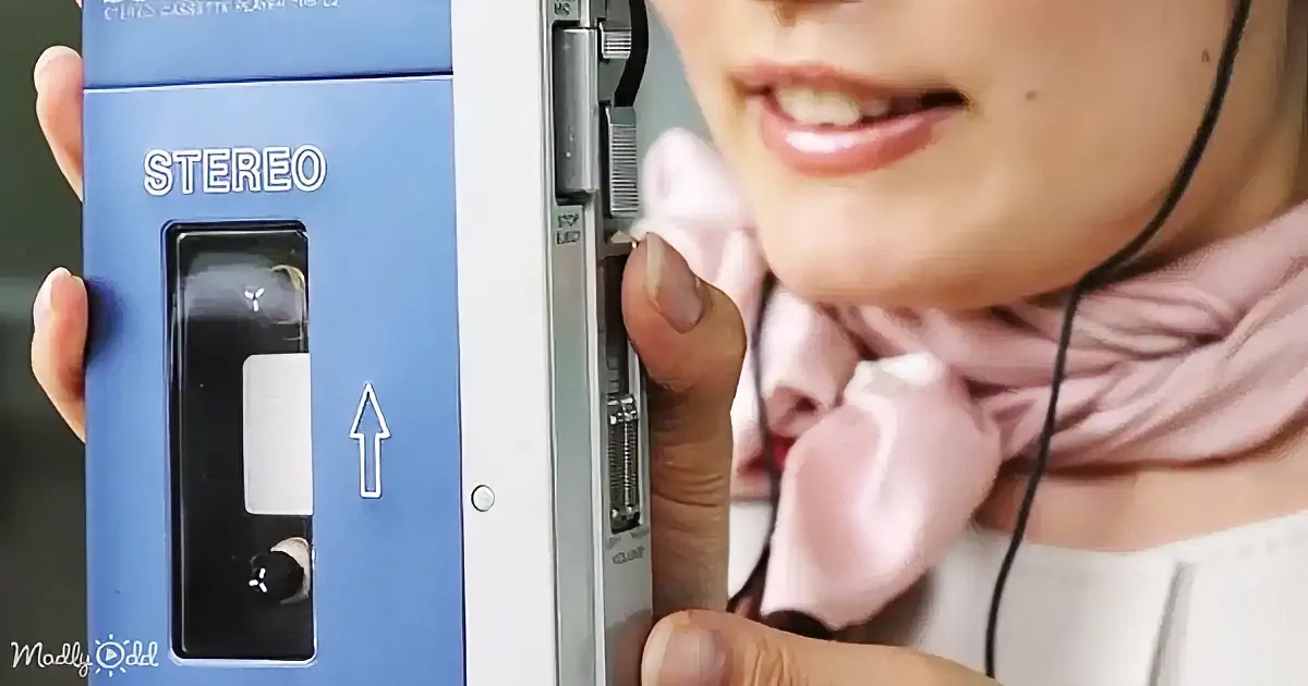 A person holds a blue stereo cassette player, inserting a cassette tape into it.