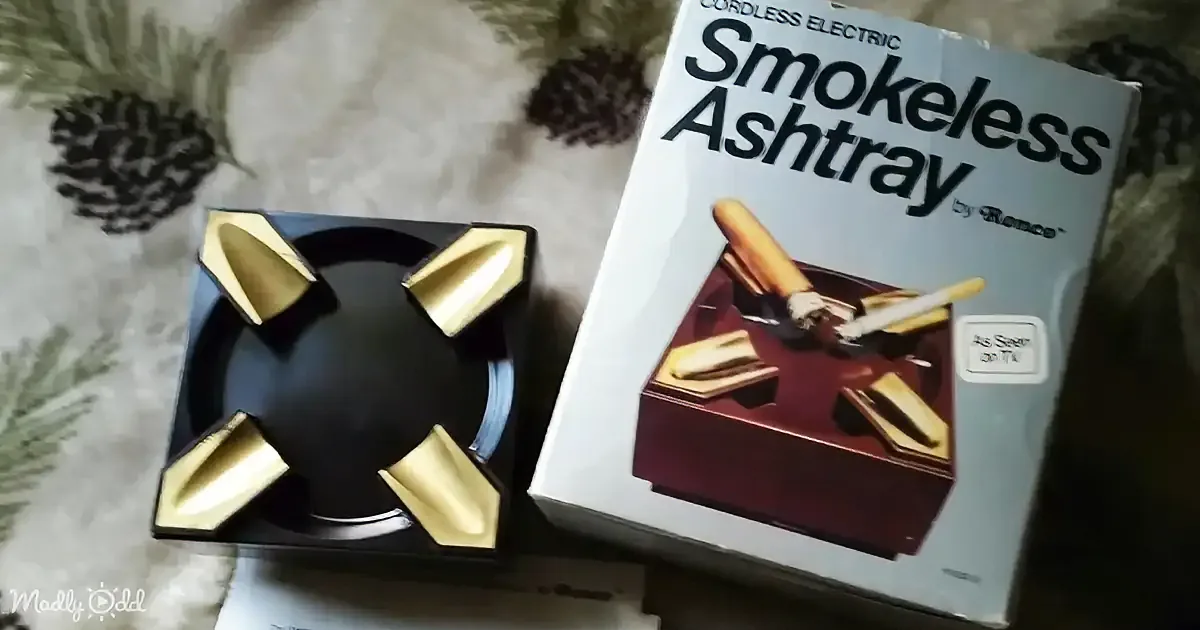 A smokeless ashtray with four compartments sits next to its box, both on a patterned surface.