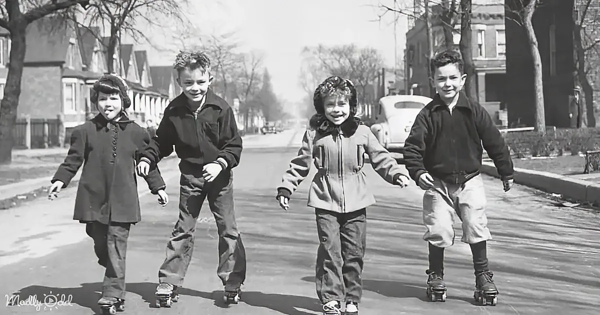 Four children roller skate down a suburban street, smiling and enjoying the sunny day.