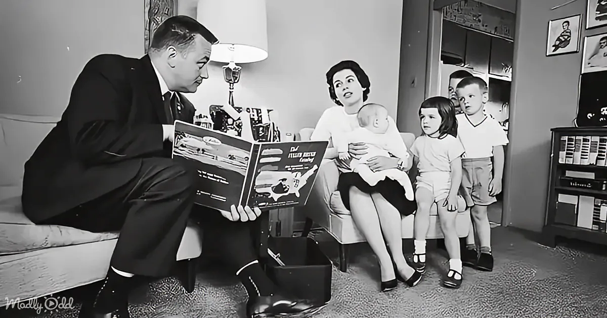 A man in a suit reads a book to a family sitting on a couch in a vintage living room.