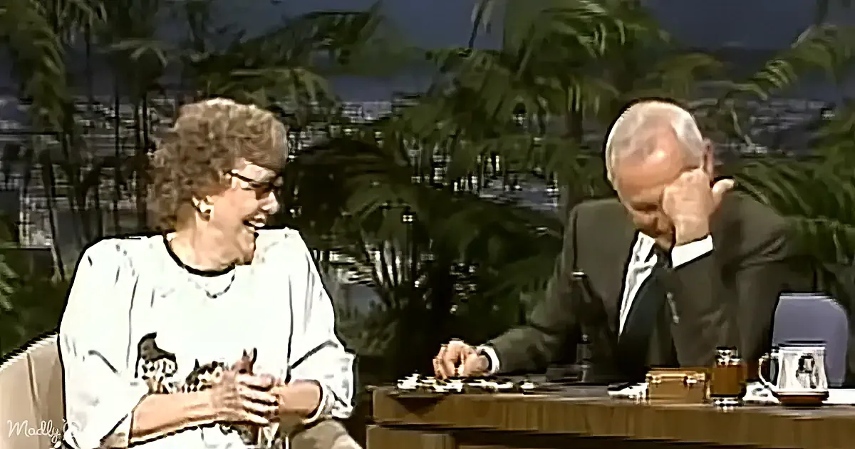 Woman in white shirt with cats laughing, man in suit holding head, tropical background.