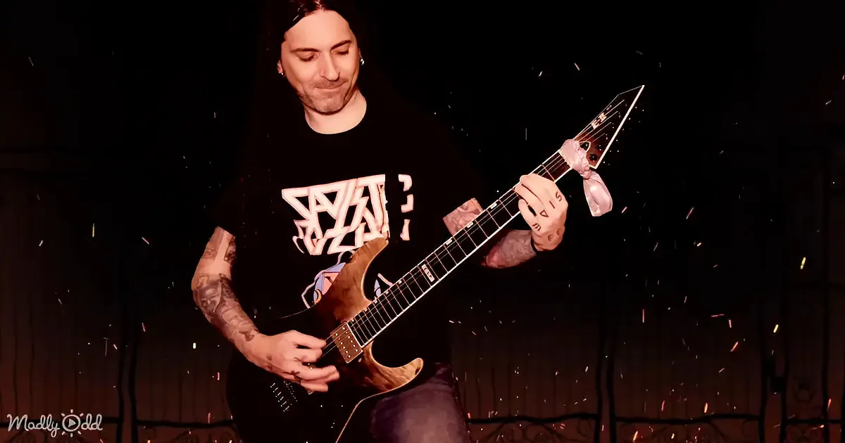 A guitarist with tattoos plays an electric guitar on stage amidst sparks.