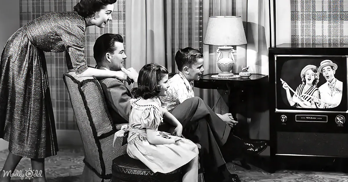 A family gathers around a vintage television, watching a show together in a cozy living room.