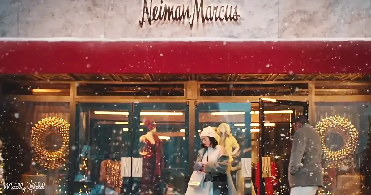 A woman with shopping bags stands in front of a Neiman Marcus store adorned with holiday decorations.