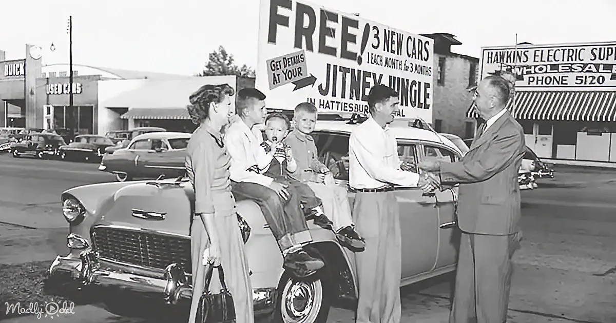 A family stands by a car in front of a sign advertising free new cars at the Jitney Jungle in Hattiesburg.