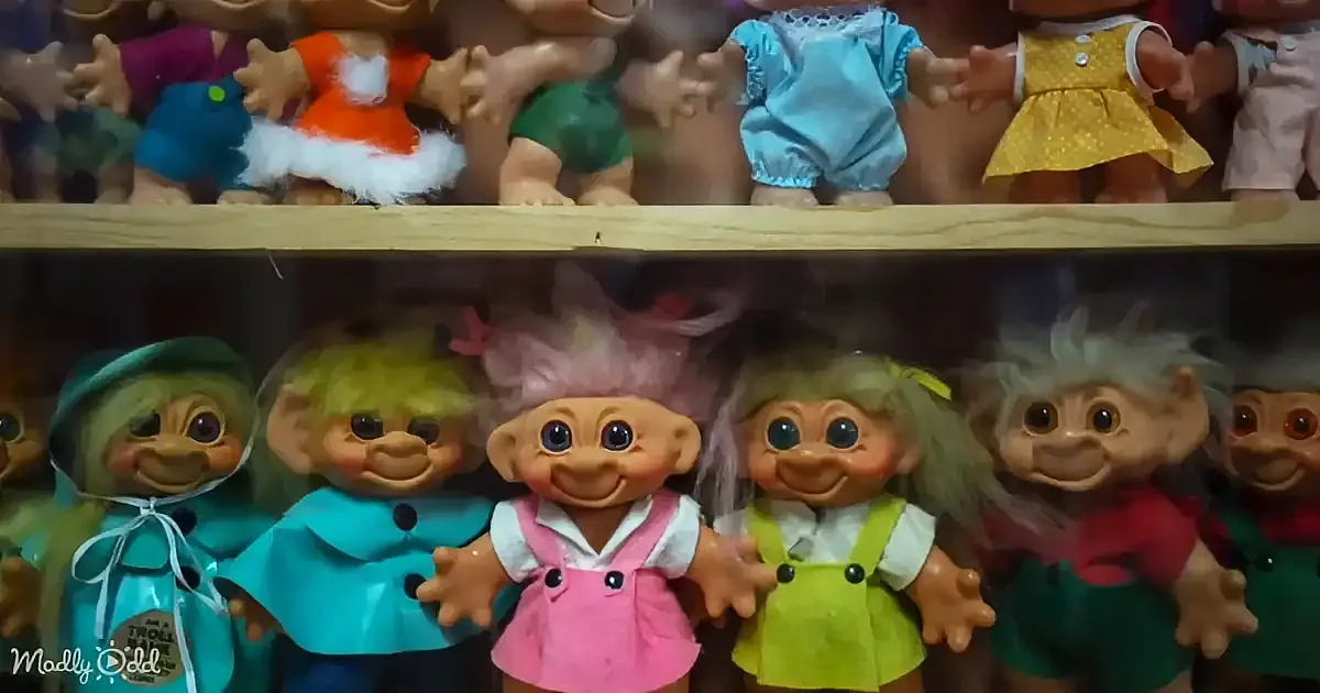 A row of colorful troll dolls with various outfits and hairstyles displayed on shelves.