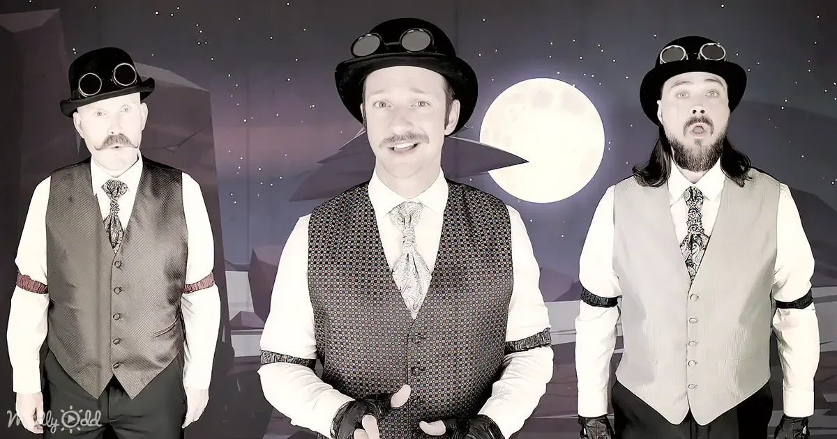 A man in a steampunk-inspired outfit with goggles and a top hat stands against a night sky backdrop.