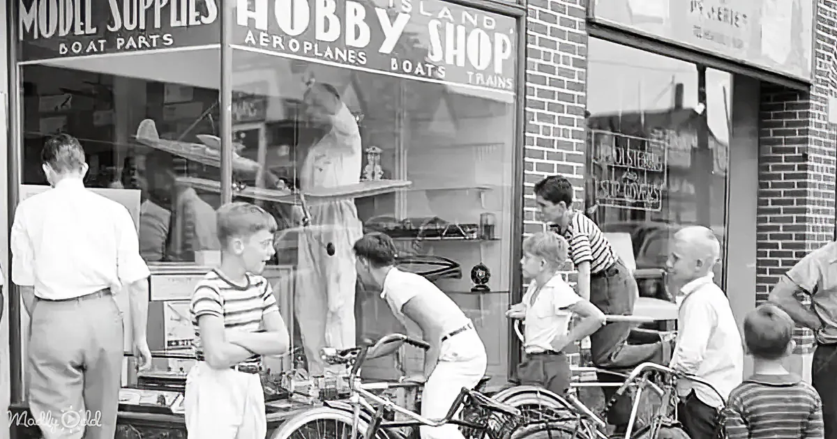 Children gather outside a hobby shop, with bicycles and toy planes visible in the window display.