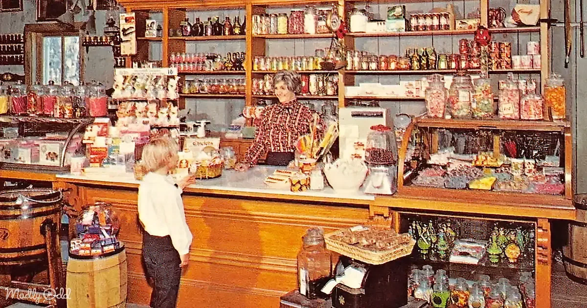A child stands at a counter in a vintage candy store, interacting with a woman behind the counter.