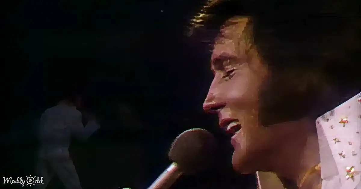 A close-up of a performer singing into a microphone, wearing a white outfit with gold embellishments.