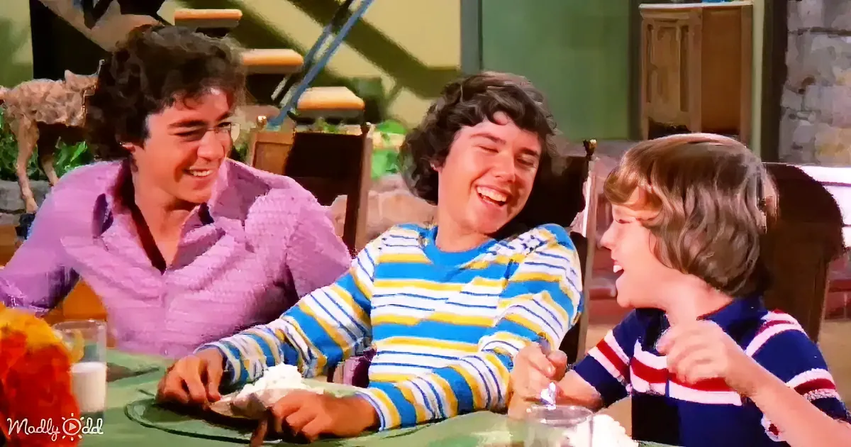 Three people sitting at a table, laughing and enjoying a meal together.