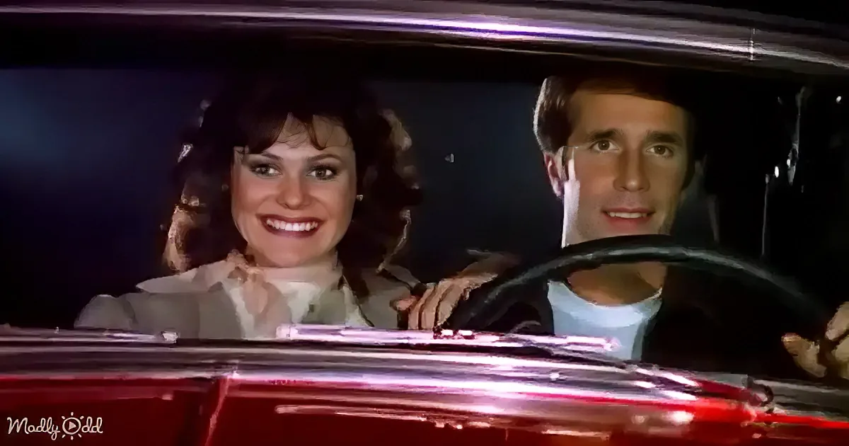 A man and woman smile in a car, the woman in the passenger seat, the man driving.