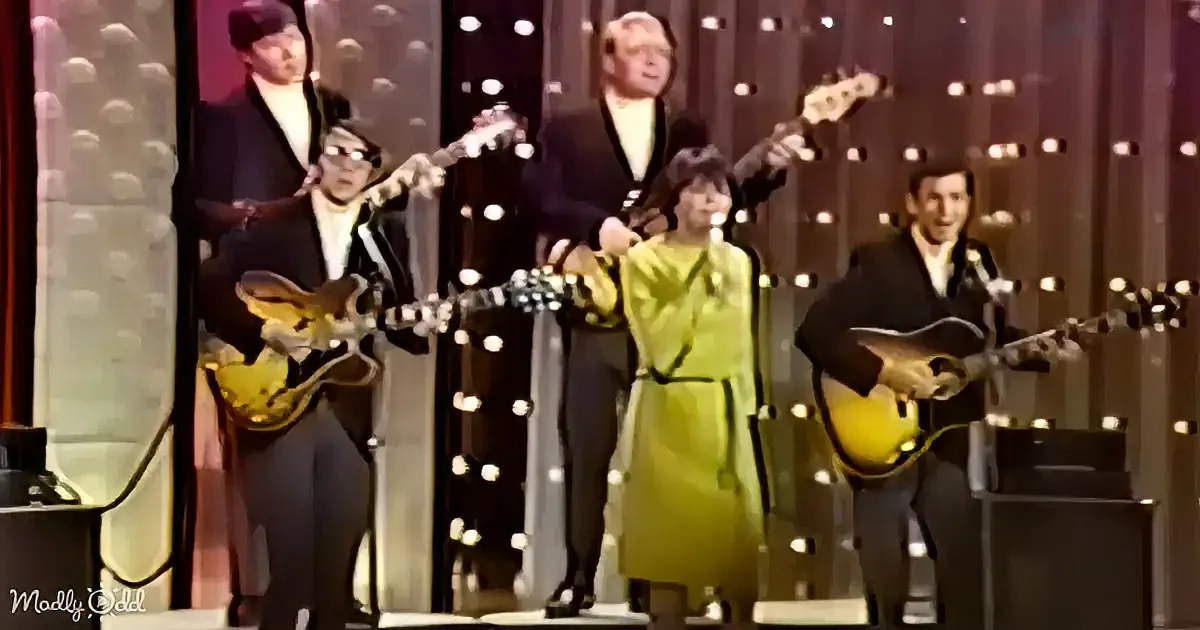A group of musicians in formal attire perform on stage with microphones and guitars.