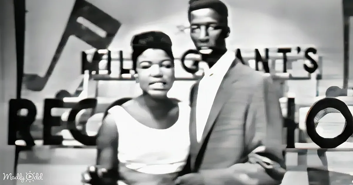 A woman in a white dress and a man in a suit stand in front of a sign that reads "Milt Grant's Record Shop."
