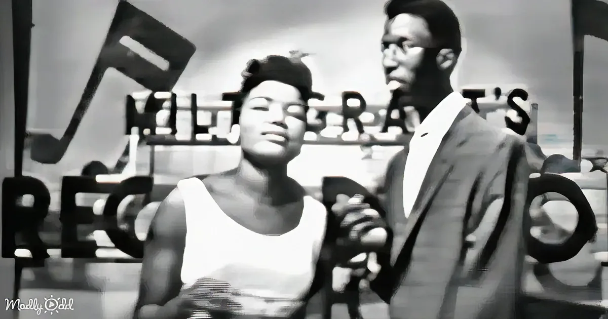 A woman in a white dress sits with a man in a suit, both smiling, in a vintage setting with "RECORDS" visible.