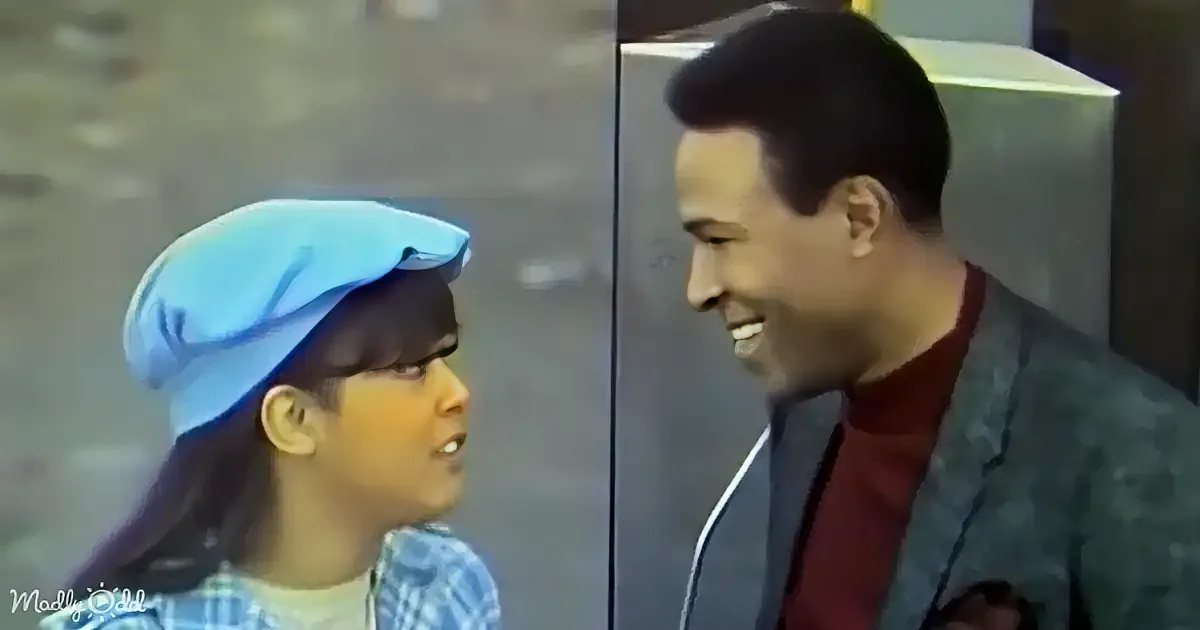 A smiling man and a child in a blue hat share a joyful moment, both looking at each other.