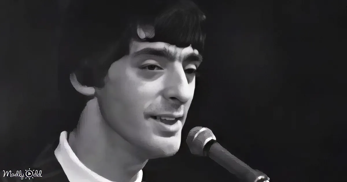 A person wearing a white shirt sings into a microphone, captured in a close-up shot.