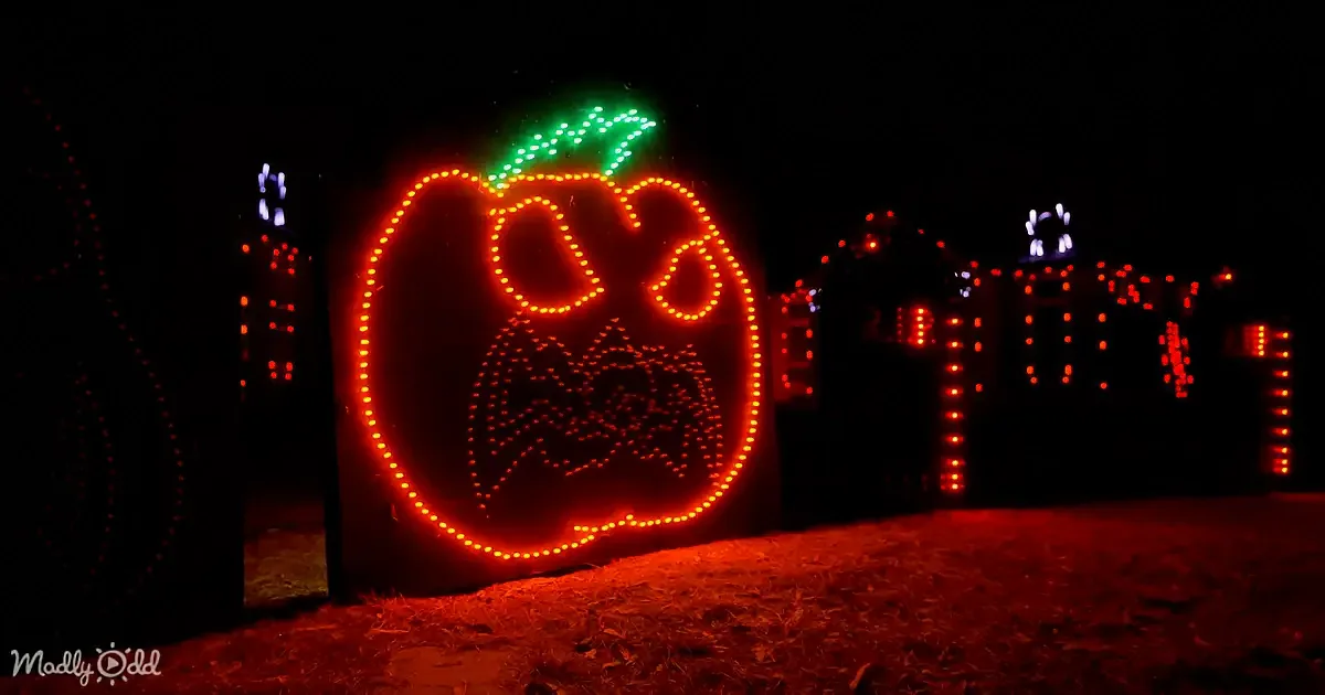 A glowing orange jack-o'-lantern sign with a carved face stands illuminated against a dark background.