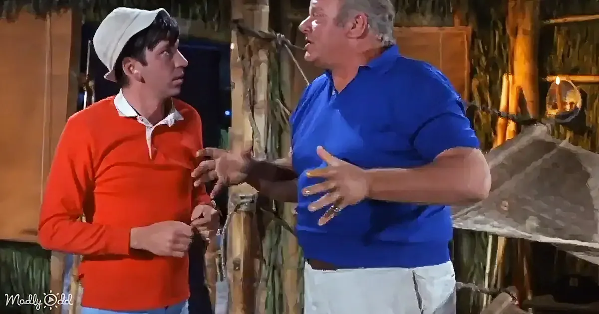 A man in a blue shirt gestures emphatically while talking to another man in a red sweater and white hat.