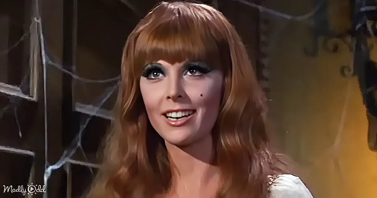 A woman with long, wavy red hair and dramatic makeup smiles in a warmly lit setting.