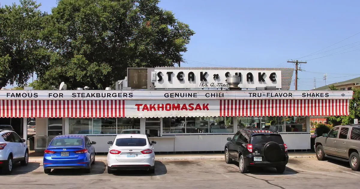 Steak 'n Shake Drive-In with classic cars parked in front, nostalgic 1950s vibe.