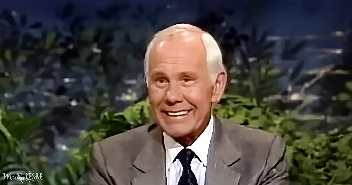 A man in a suit and tie smiles, set against a backdrop of greenery and a dark sky.