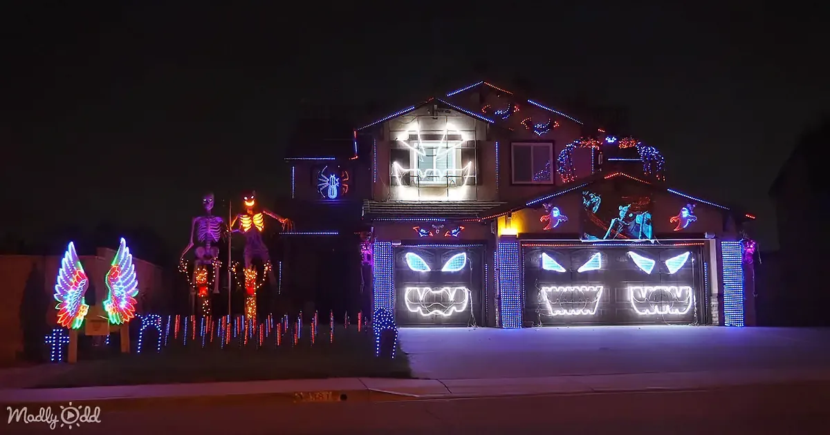 A house adorned with Halloween lights and decorations, featuring glowing faces, skeletons, and a spider web, creating a...