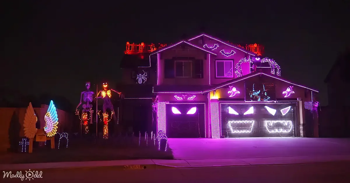 A house is decorated with Halloween lights, featuring skeletons, bats, and glowing eyes, creating a spooky atmosphere.