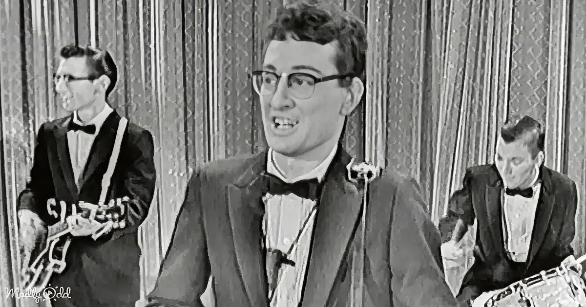 A man in a tuxedo sings into a microphone, accompanied by musicians in a formal setting.