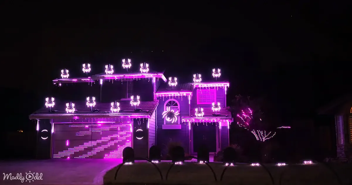 A house is adorned with vibrant purple Halloween lights, creating a spooky and festive atmosphere.